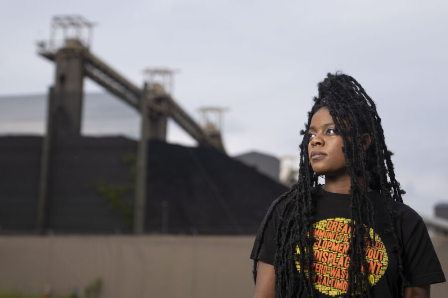 Shashawnda Campbell, community organizer with South Baltimore Community Land Trust, a local nonprofit working on affordable housing, in front of piles of coal at the CSX facility in Baltimore. Baltimore City recently decided to close the only recreation facility available to Curtis Bay residents dealing with coal dust and other hazards from the facility. Credit: Jessica Gallagher/Baltimore Banner.