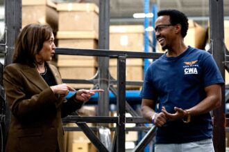Vice President Kamala Harris speaks with employee Bashir Abdi as she tours the facility of bus manufacturer New Flyer in Saint Cloud, Minnesota on February 9, 2023, after a State of the Union address by President Joe Biden touting his administration's investments in electric vehicles.