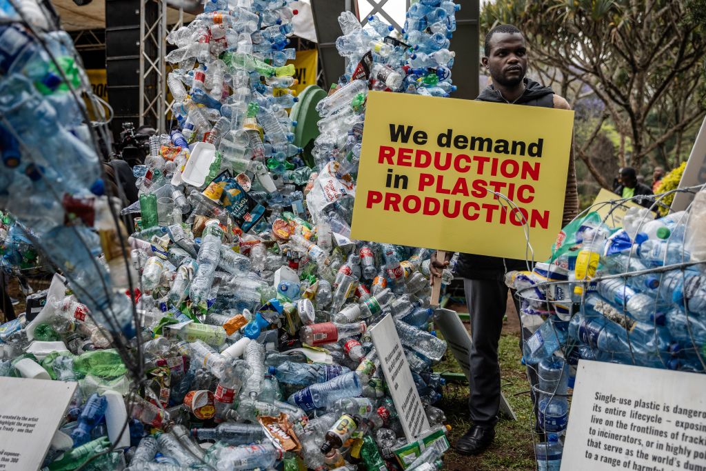 A climate activist holds a banner next to a plastic installation after marching to demand drastic reduction in global plastic production during the Break Free From Plastic Movement March ahead of the third meeting of the Intergovernmental Negotiating Committee (INC-3) in Nairobi on November 11, 2023.