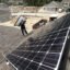 Jack Doherty, photovoltaic project manager for Revision Energy, carries a solar panel to the roof ridge of a home in OceanView at Falmouth. The company, which employs almost 200 people, has installed panels on about 50 roofs in the development. Credit: Ben McCanna/Portland Portland Press Herald via Getty Images