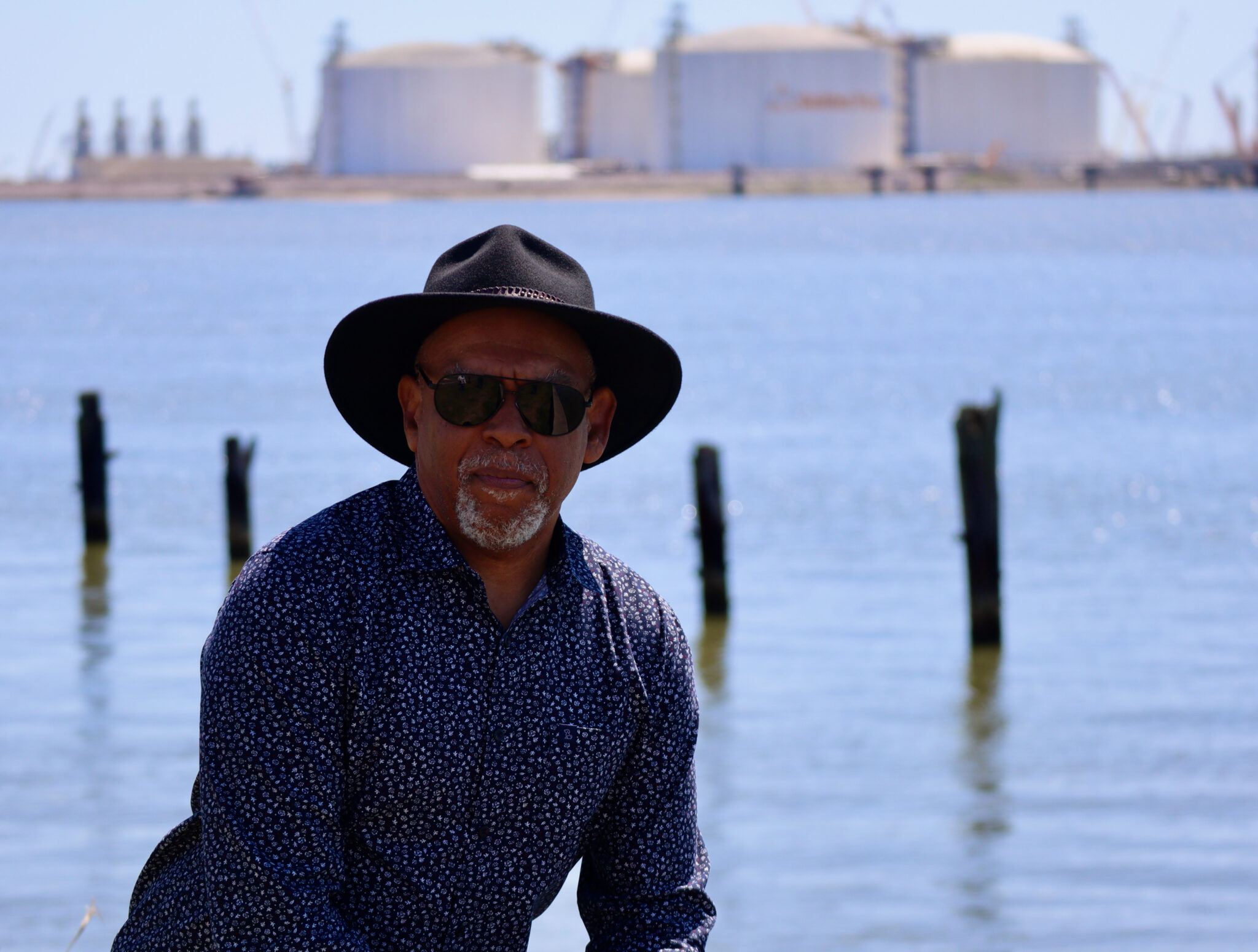John Beard Jr., the founder and executive director of the Port Arthur Community Action Network, stands in front of the ExxonMobil and QatarEnergy’s Golden Pass LNG facility, just south of Port Arthur, Texas. Beard is a retired refinery worker who first challenged the Port Arthur LNG emissions permit. Credit: James Bruggers/Inside Climate News