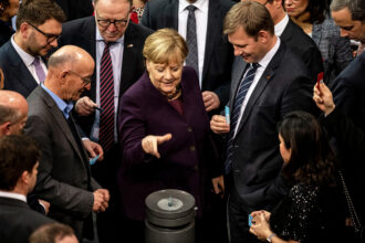 German Chancellor Angela Merkel throws her voting card into the ballot box during passage of sweeping climate legislation in December 2019.
