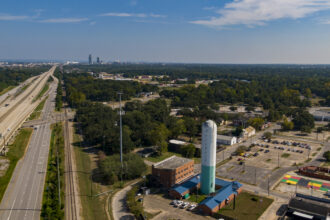 A water tower in Prichard, Alabama, a majority Black town with a crumbling water infrastructure. Mobile’s nearby skyline is visible in the background. Credit: Lee Hedgepeth/Inside Climate News