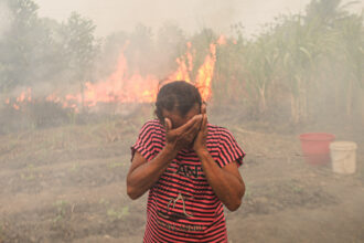 A woman reacts as a wildfire burns at Palem Raya Regency in Ogan Ilir, South Sumatera, Indonesia on September 18, 2023. Indonesian authorities are struggling to put out forest and land fires that have been engulfing many parts of the country, including fire-prone regions in Sumatra and Borneo, as the country enters the hottest day of this year's El Nino-induced dry season Credit: Muhammad A.F/Anadolu Agency via Getty Images